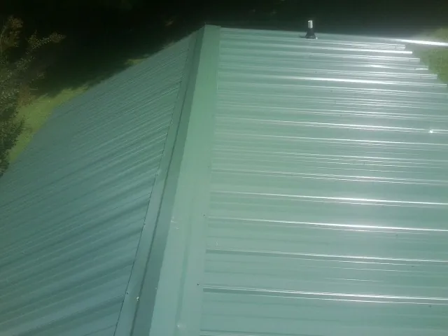 New green metal panels meeting at the ridge of a roof — Flat Roof Repair work by our crew in Weir