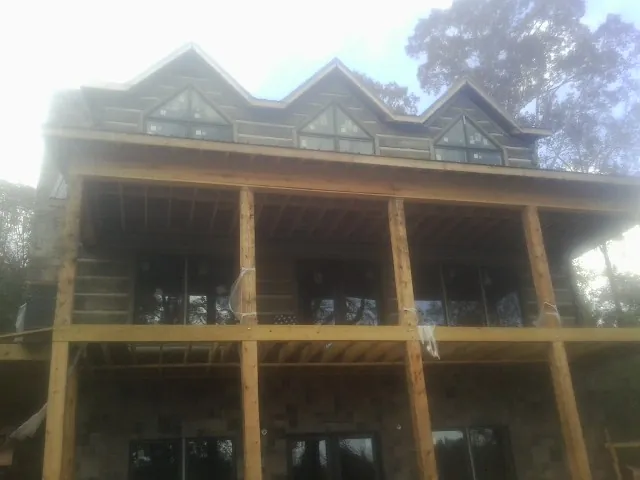 Dormers and porch framing on a large log home under construction — Roof Coating work by our crew in Weir