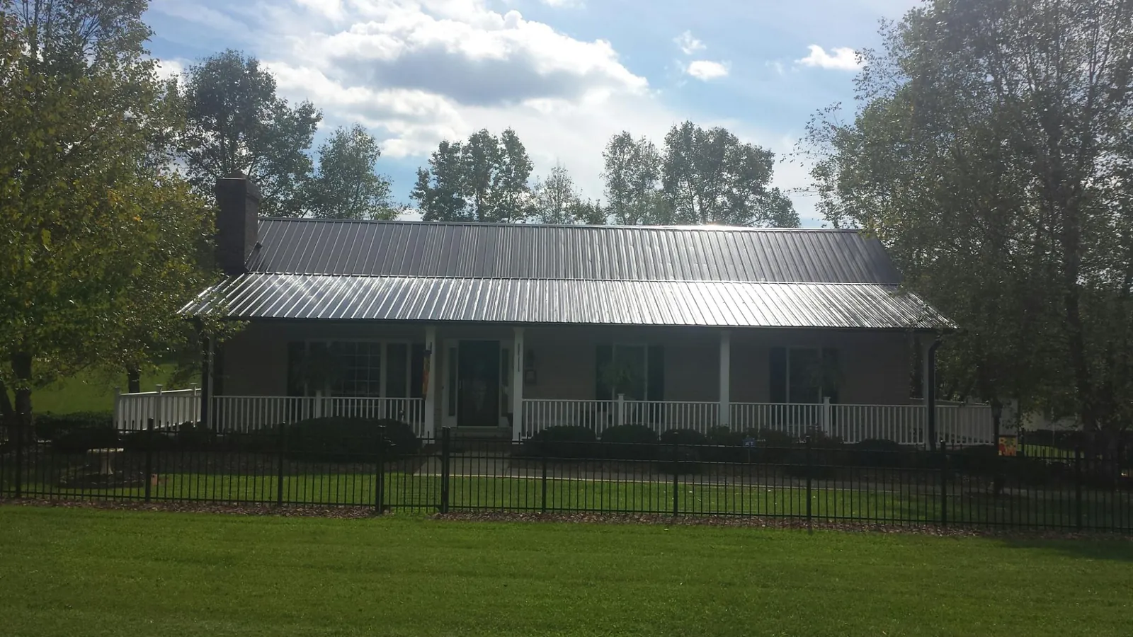 Gray metal roof on a brick ranch with a full width front porch — Gutter Guard Installation work by our crew in Weir