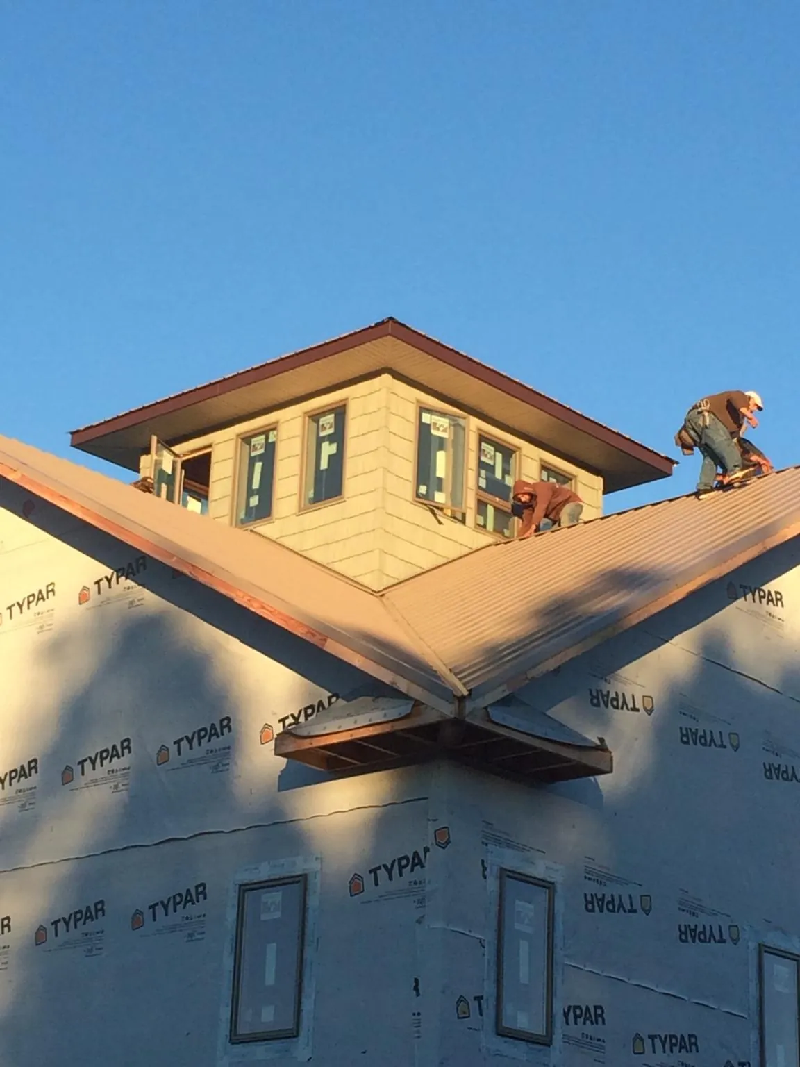 Roofers working around a rooftop cupola on a new metal roof at sunset — Roof Waterproofing in Weir by Roofing Brothers